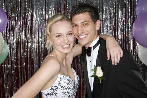 A blonde teenage girl and dark haired teenage boy smile for a photo at their prom at mercure hotels