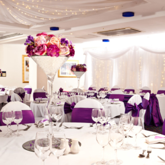 The Central Avenue Suite at Mercure Bolton Georgian House Hotel set up ready for a wedding breakfast, white linen, purple sashes and floral centrepieces